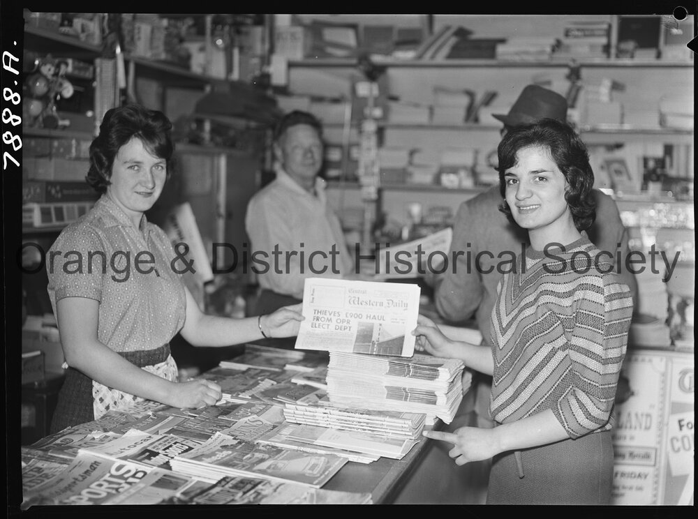 Shop assistant selling a Central Western Daily newspaper at Jones' Newsagency
