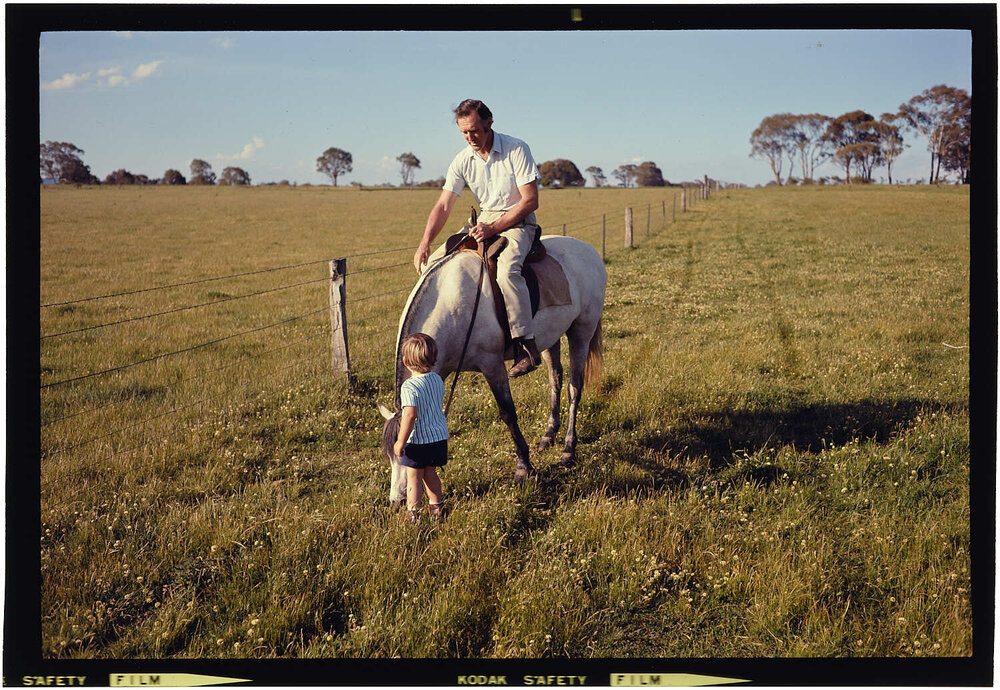 Man on horse with boy standing on ground